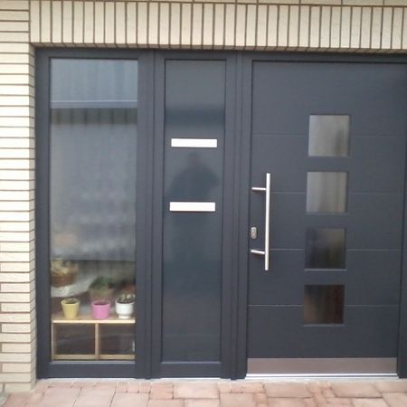 Moderne schwarze Haustür mit Glasfüllung an einer Backsteinfassade